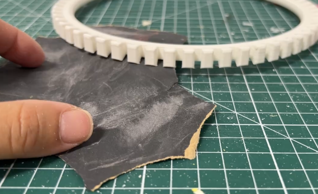 Image of white plastic loom next to some sandpaper.