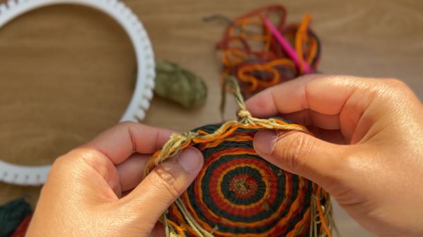 Image of the woven piece separated from the white loom, which can be seen in the background.